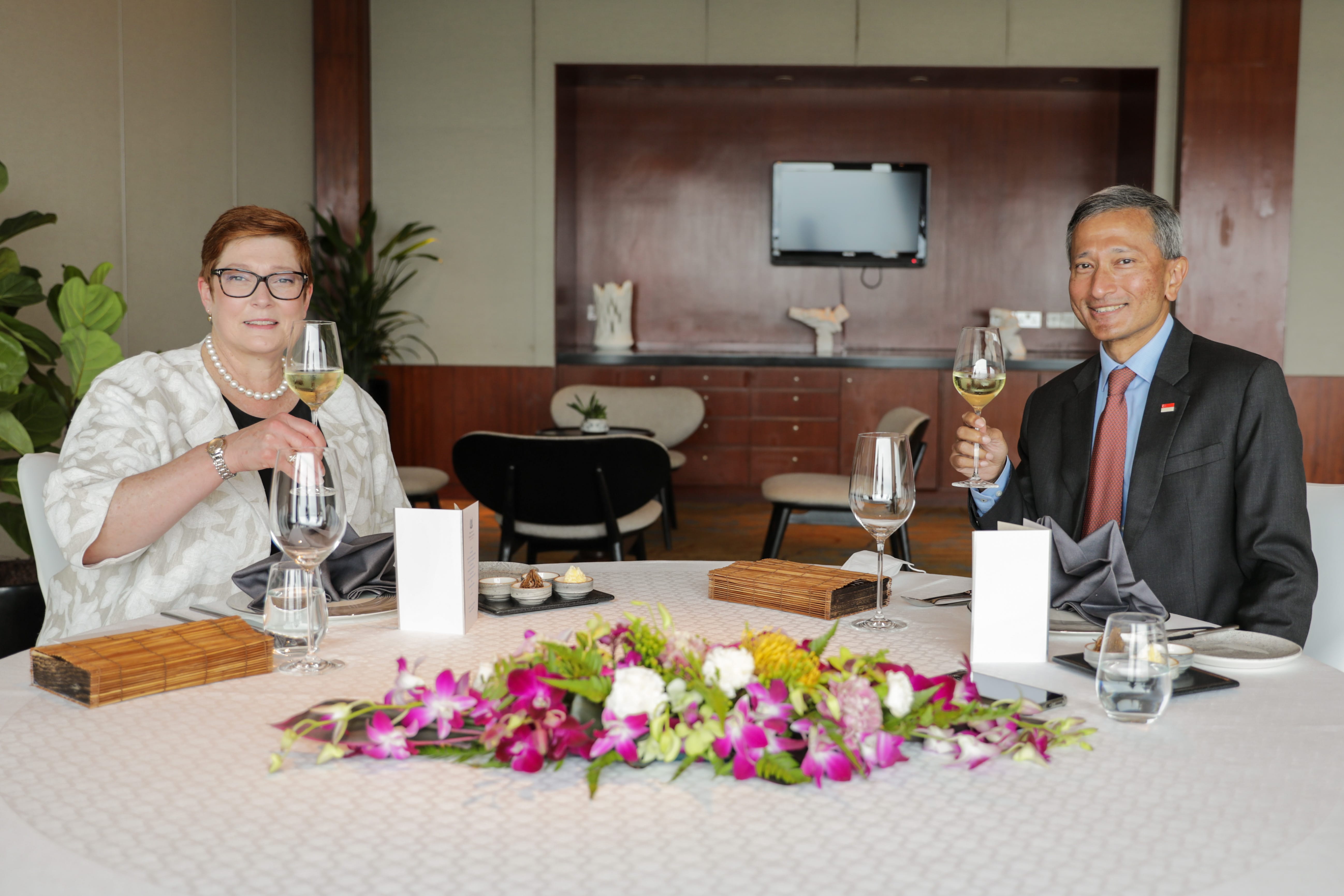 Singapore President Tharman Shanmugaratnam, female guest, toasting wine over flower centerpiece.